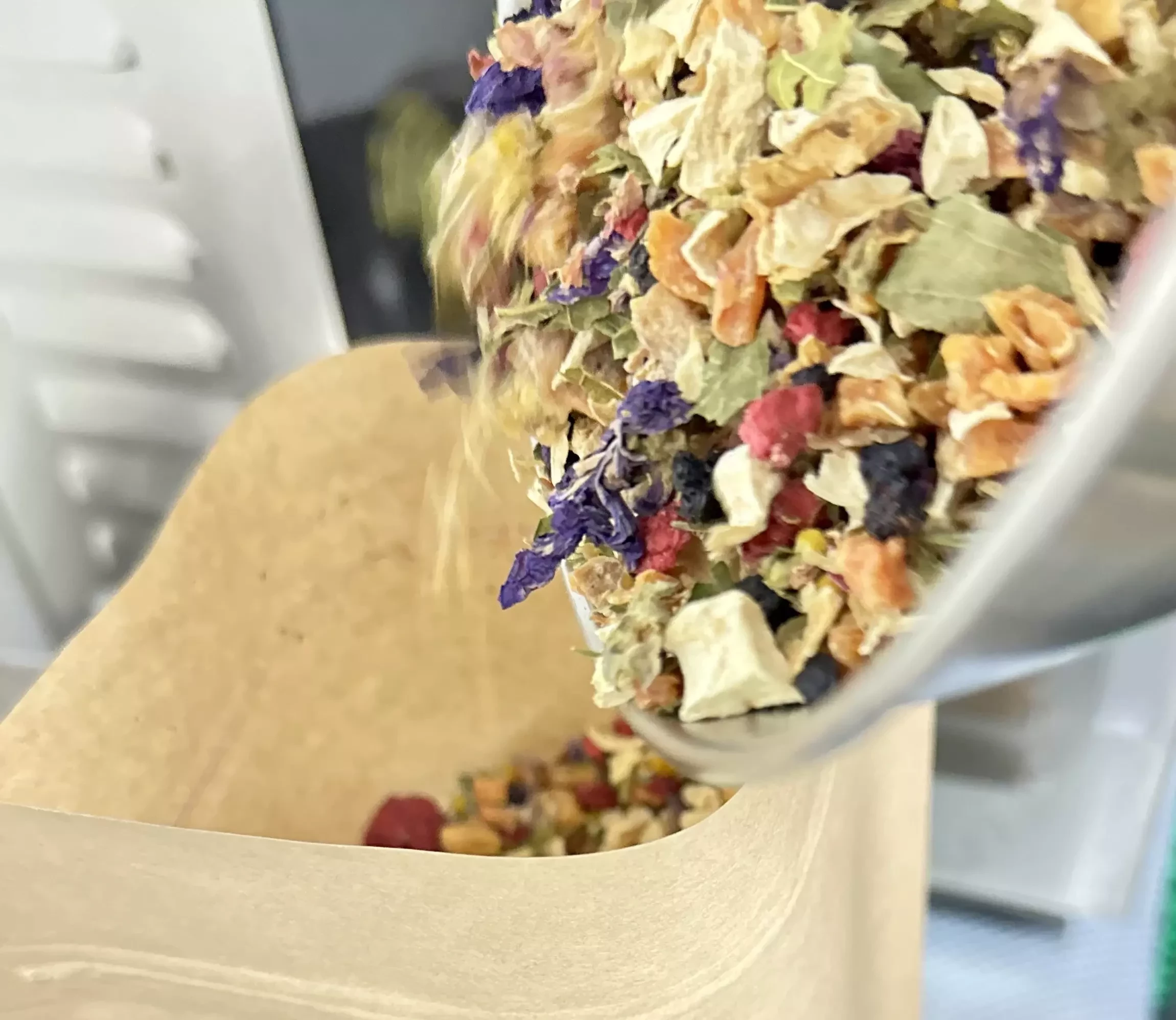 Getrocknete Gemüsemischung mit Beeren und Blüten werden in eine Tüte gefüllt