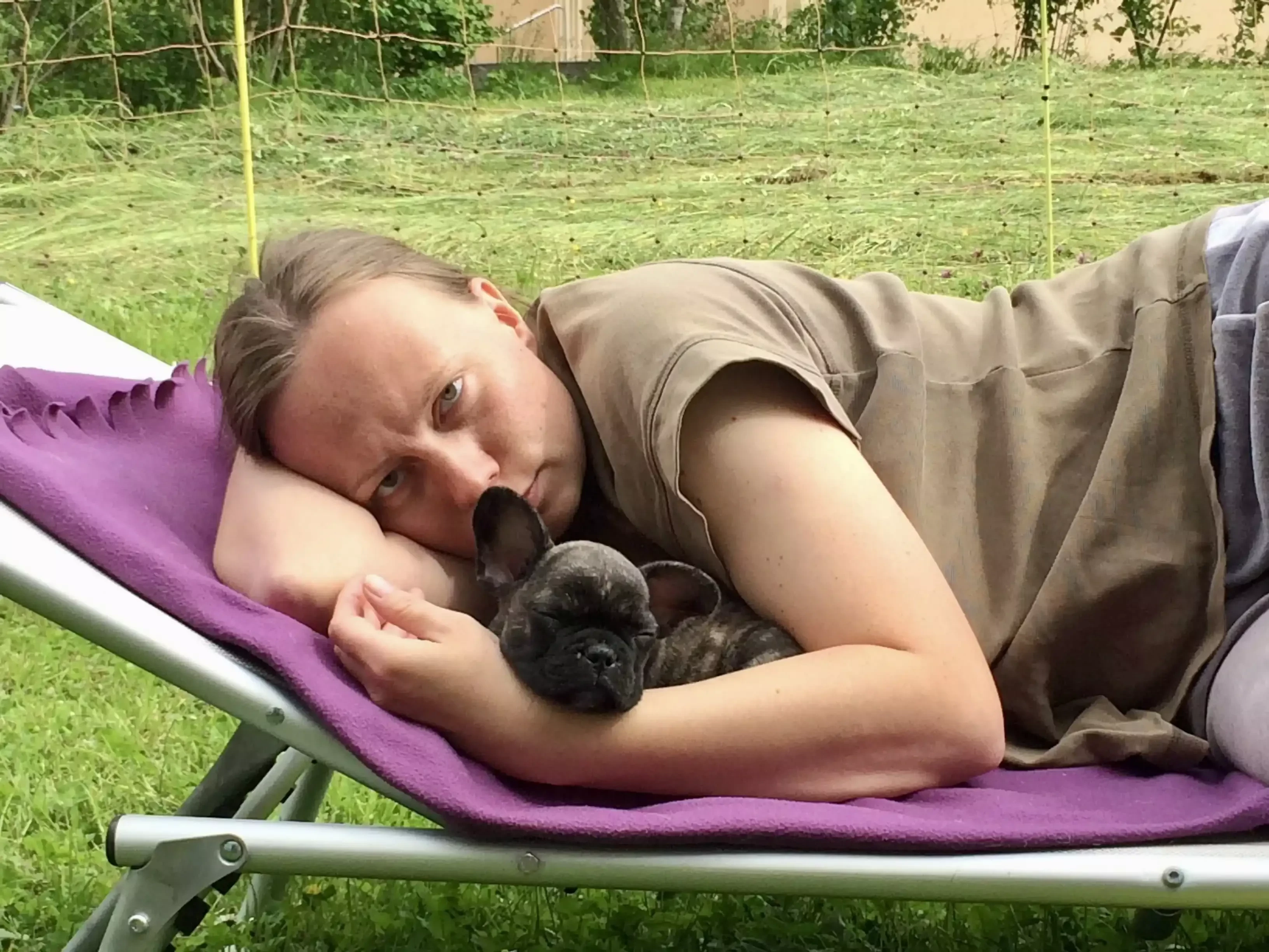 Daniela liegt mit Kostas als Welpe auf einer Gartenliege